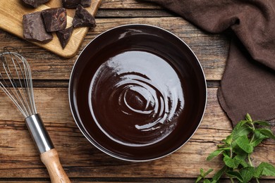 Delicious chocolate cream, whisk and mint on wooden table, flat lay