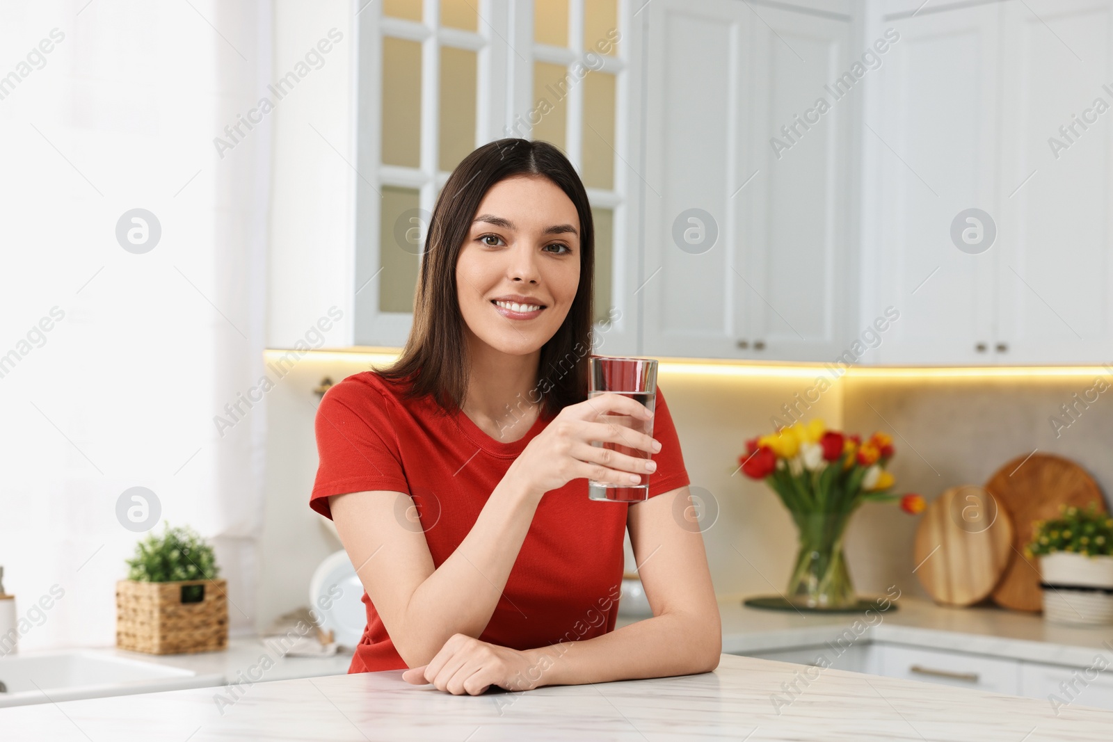 Photo of Young woman with glass of water in kitchen