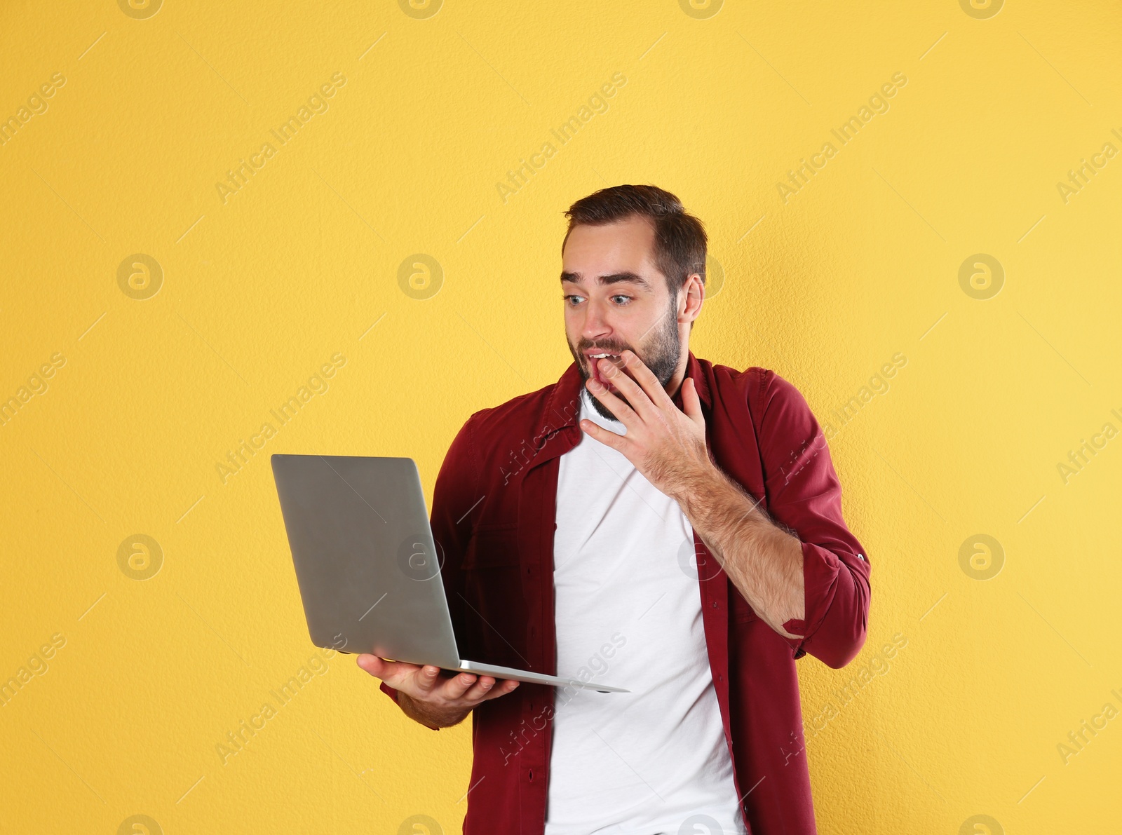 Photo of Emotional young man with laptop celebrating victory on color background