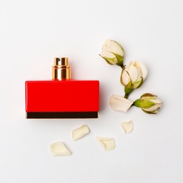 Red bottle of perfume with beautiful flowers on white background