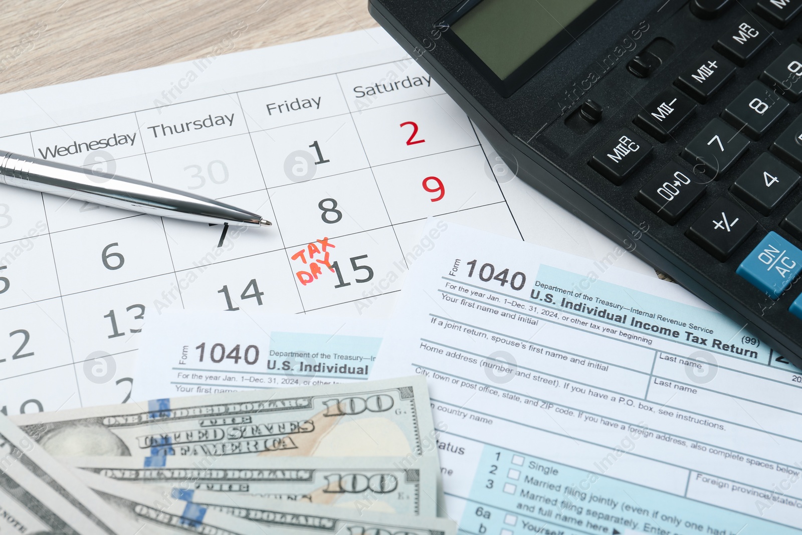 Photo of Tax day. Calendar with date reminder, documents, dollar banknotes, pen and calculator on table