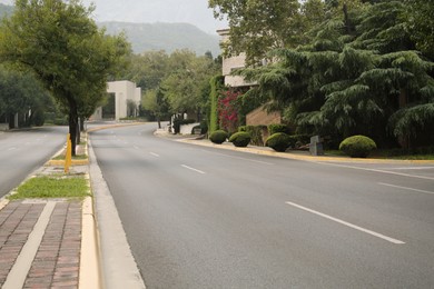 Beautiful city street with wide asphalt road and green trees