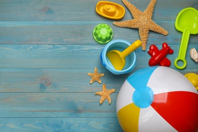 Photo of Beach ball and sand toys on light blue wooden background, flat lay. Space for text