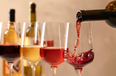 Pouring wine from bottle into glass on blurred background, closeup