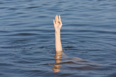 Photo of Drowning woman reaching for help in sea, closeup