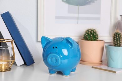 Color piggy bank on table in room. Cute interior element