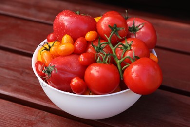 Bowl with fresh tomatoes on wooden table