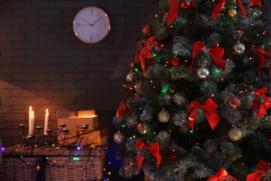 Photo of Christmas tree with beautiful decorations and glowing lights indoors. Stylish room interior