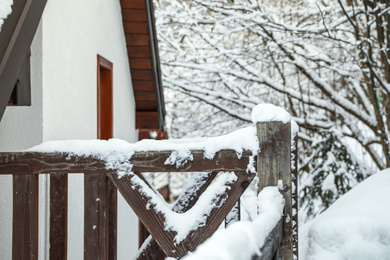 Wooden fence covered with snow near house. Winter vacation