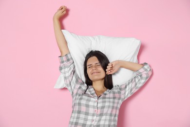 Photo of Sleepy young woman on soft pillow against pink background