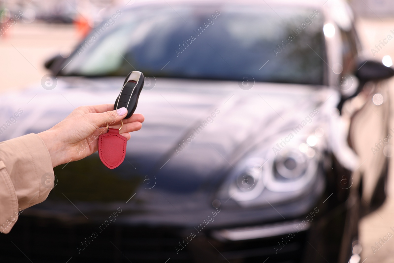 Photo of Woman holding car flip key near her vehicle outdoors, closeup