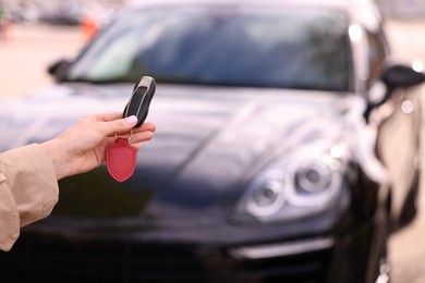 Photo of Woman holding car flip key near her vehicle outdoors, closeup