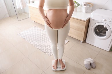 Photo of Pregnant woman standing on scales in bathroom, closeup