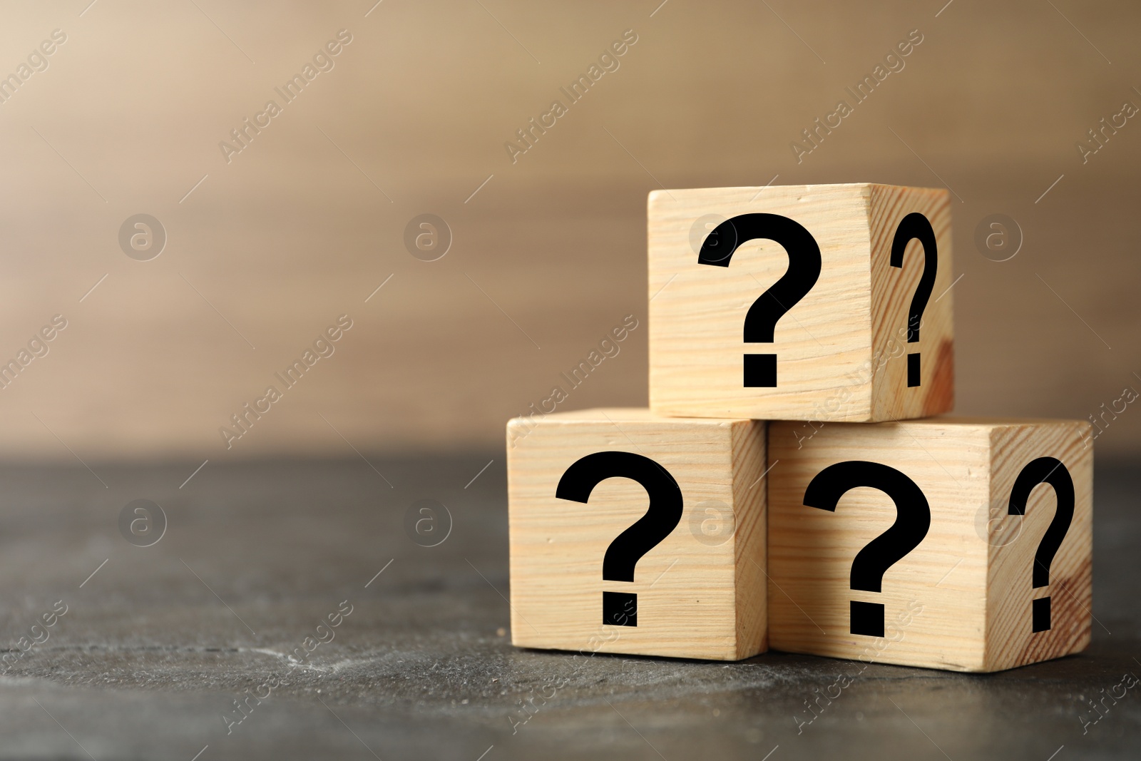 Photo of Wooden cubes with question marks on grey stone table, closeup. Space for text