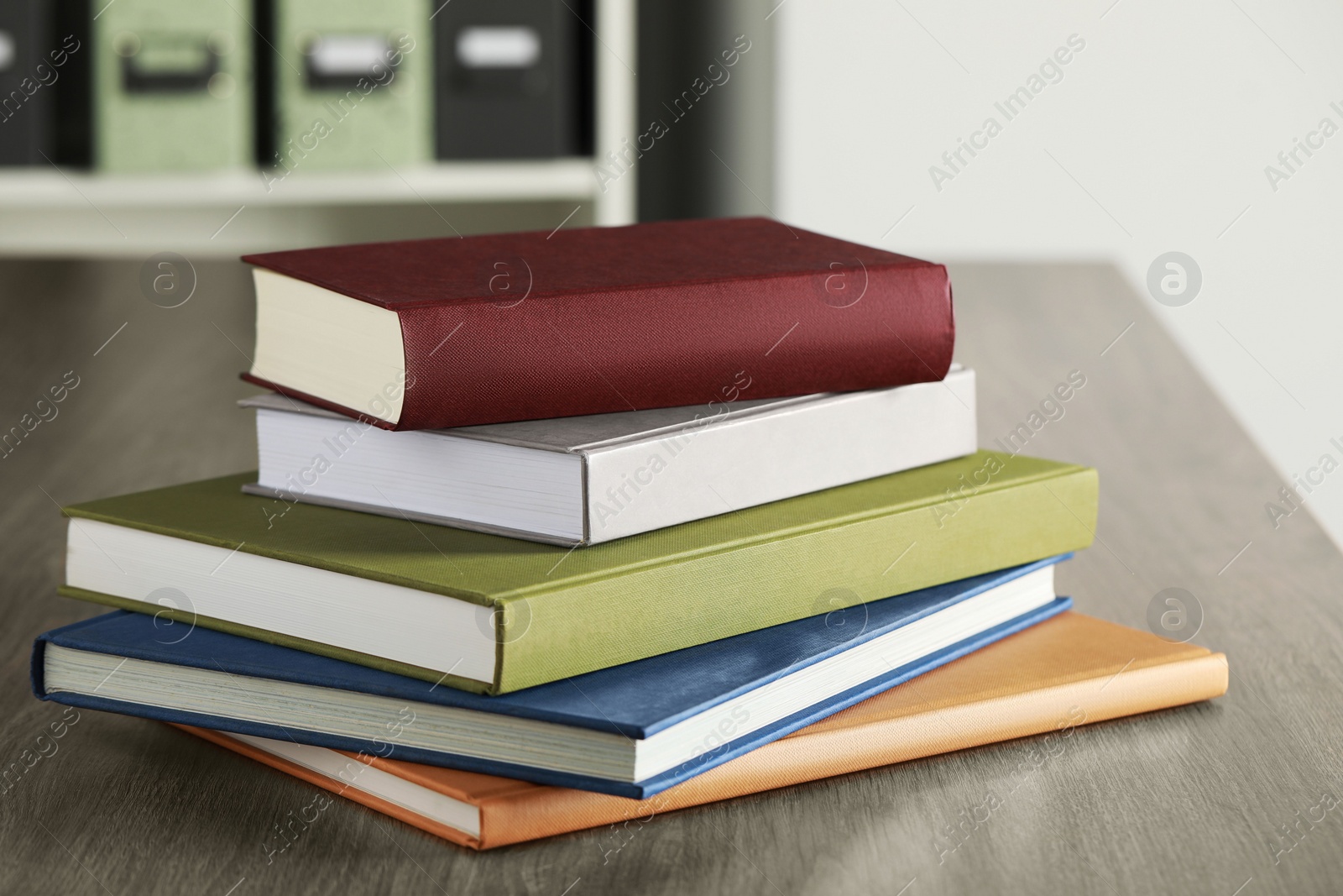 Photo of Many different books stacked on wooden table indoors