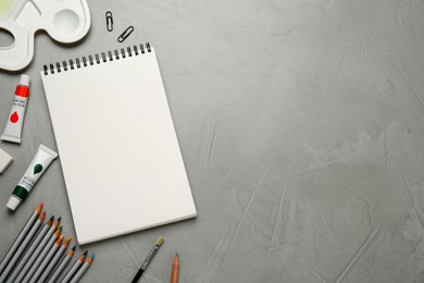 Flat lay composition with blank sketchbook on light grey stone table. Space for text