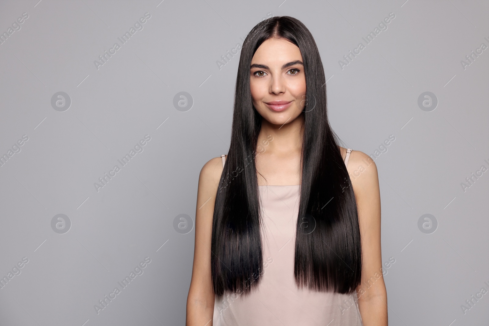 Photo of Portrait of beautiful young woman with healthy strong hair on light grey background, space for text