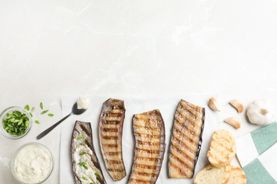 Delicious grilled eggplant slices with sauce on grey table, flat lay. Space for text