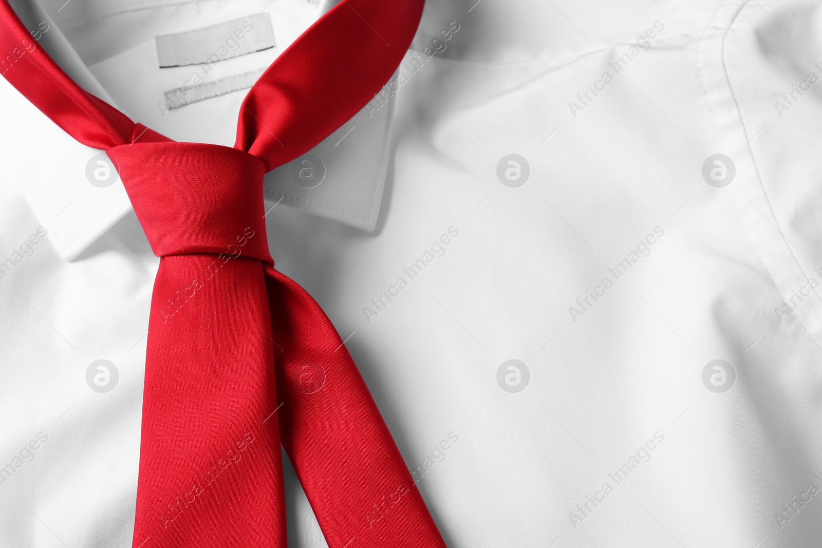 Photo of Red male necktie on white shirt, closeup. Space for text