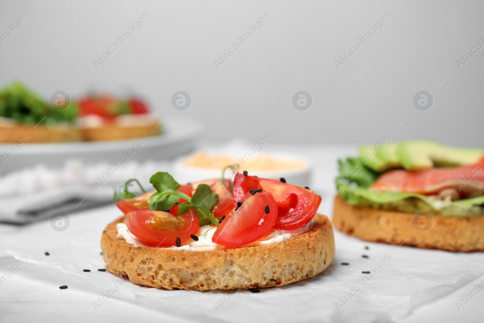 Photo of Tasty rusks with different toppings on white table, closeup