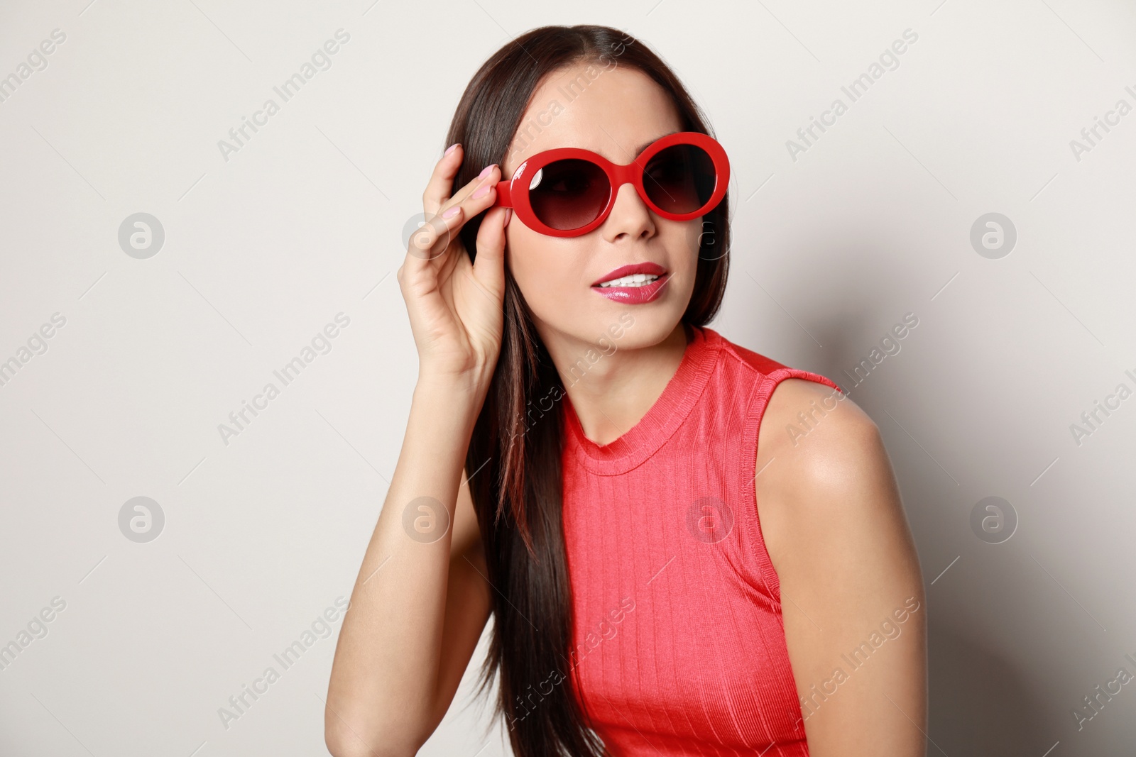 Photo of Beautiful woman in stylish sunglasses on light background