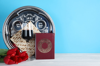 Photo of Symbolic Pesach (Passover Seder) items on white wooden table. Space for text