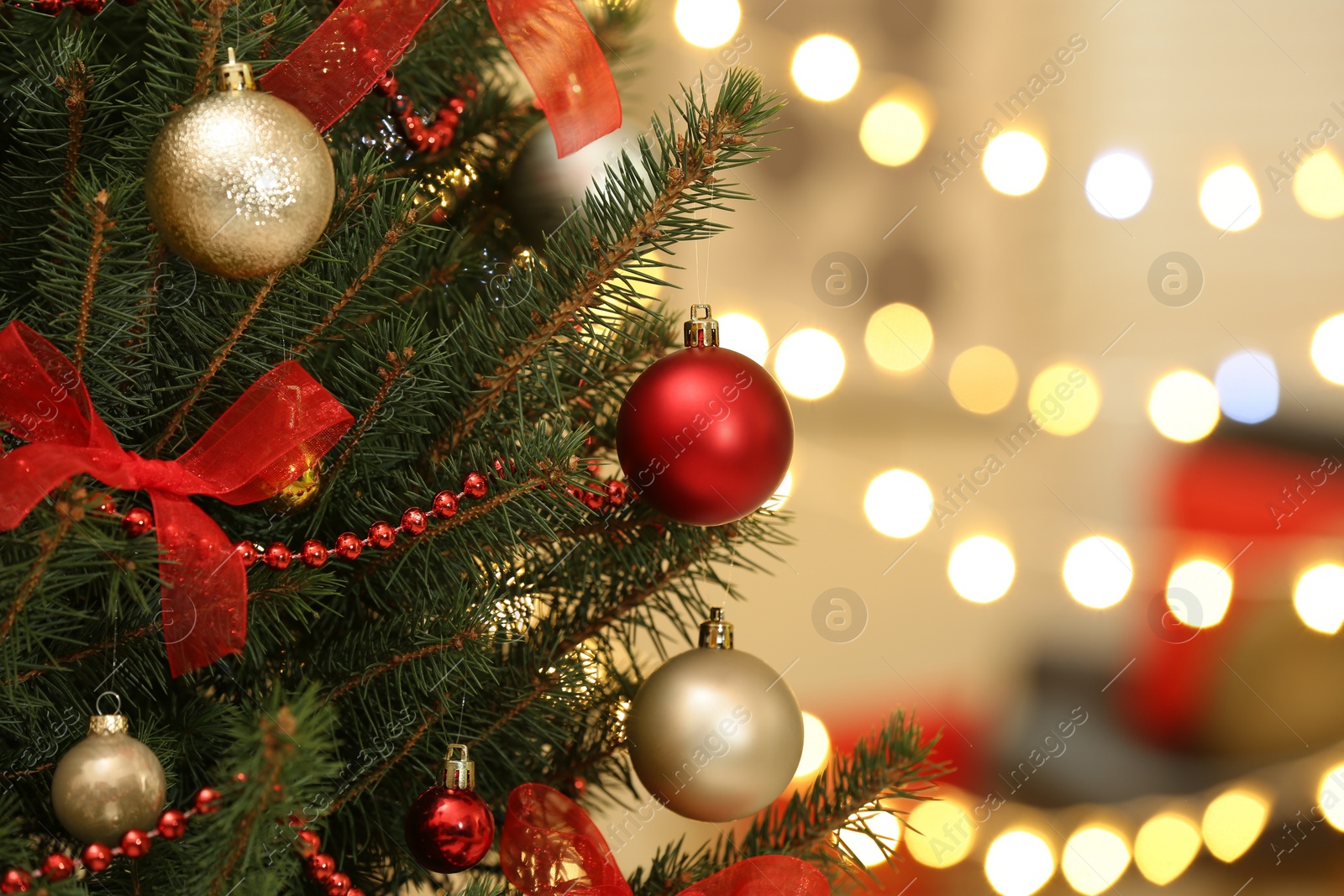 Photo of Color holiday baubles hanging on Christmas tree against blurred lights