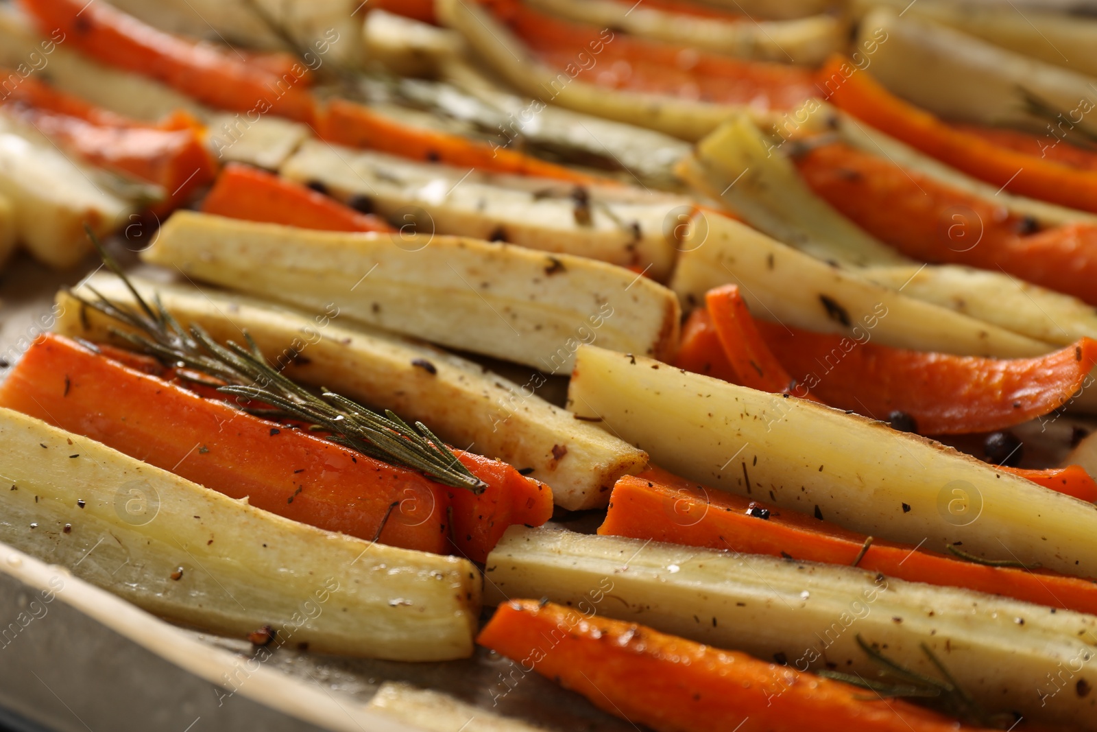 Photo of Delicious baked parsnips and carrots with rosemary on baking tray, closeup