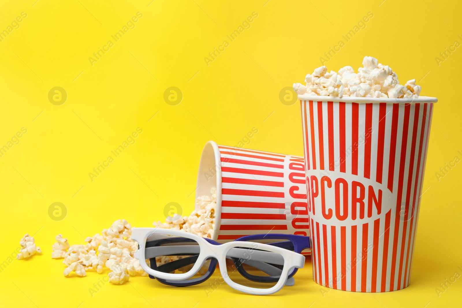 Photo of 3D glasses and popcorn on yellow background, space for text. Cinema snack