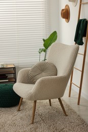 Photo of Comfortable armchair with cushion in living room. Interior design
