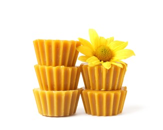 Photo of Stack of natural beeswax cake blocks and flower on white background