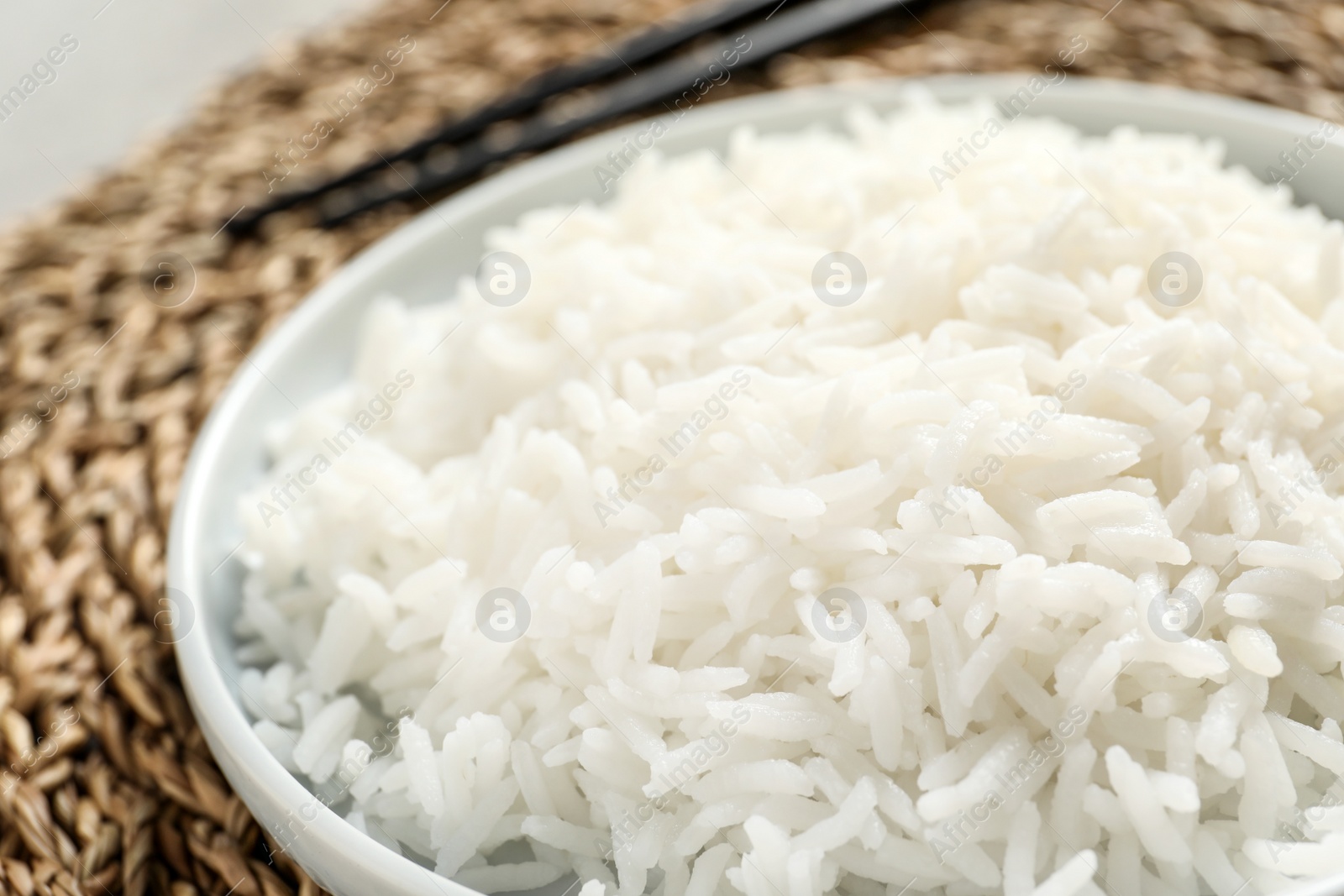 Photo of Plate of tasty cooked rice on wicker mat, closeup