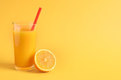 Glass of orange juice with fresh fruit on color background