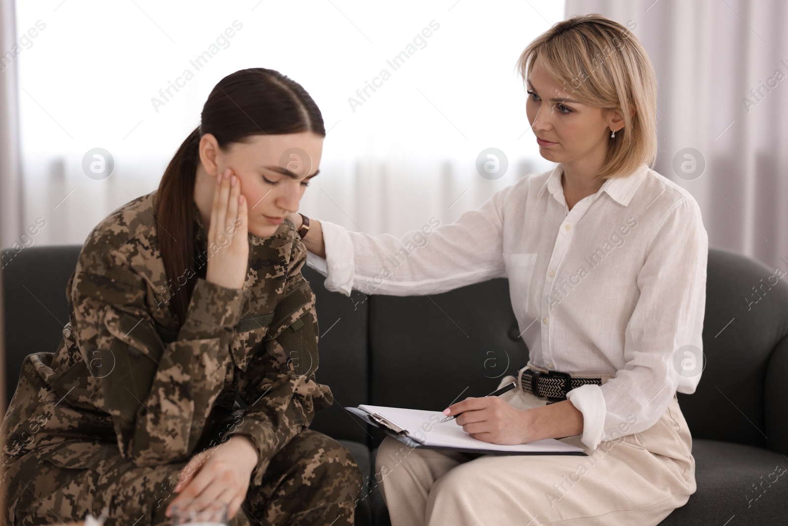 Photo of Psychotherapist working with military woman on sofa in office