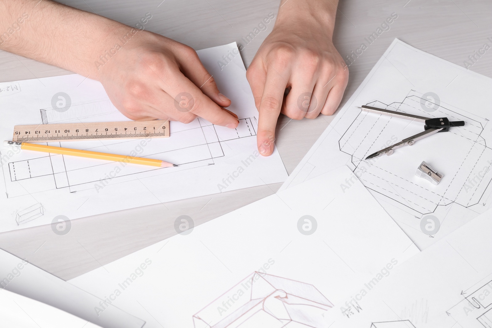 Photo of Man creating packaging design at light wooden table, closeup