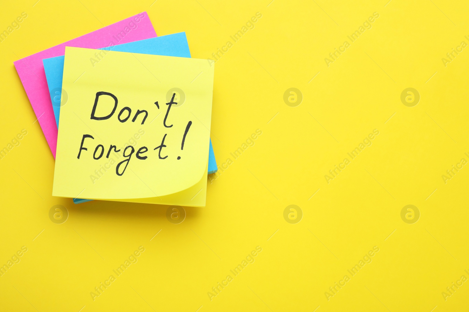 Photo of Paper note with phrase Don' t Forget on yellow background, top view. Space for text