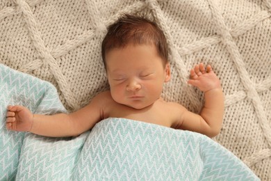Cute newborn baby sleeping on beige blanket, top view