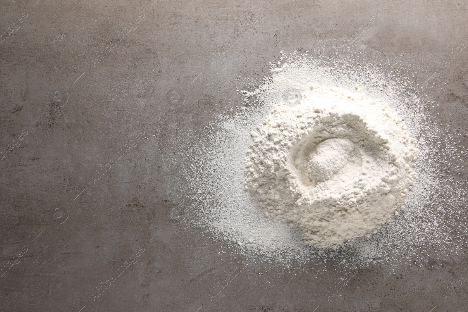 Photo of Pile of flour on grey textured table, top view. Space for text