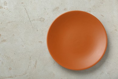 Photo of Empty orange ceramic plate on light grey table, top view. Space for text