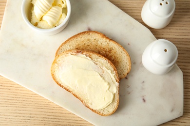 Tasty bread with butter served for breakfast on wooden table, top view