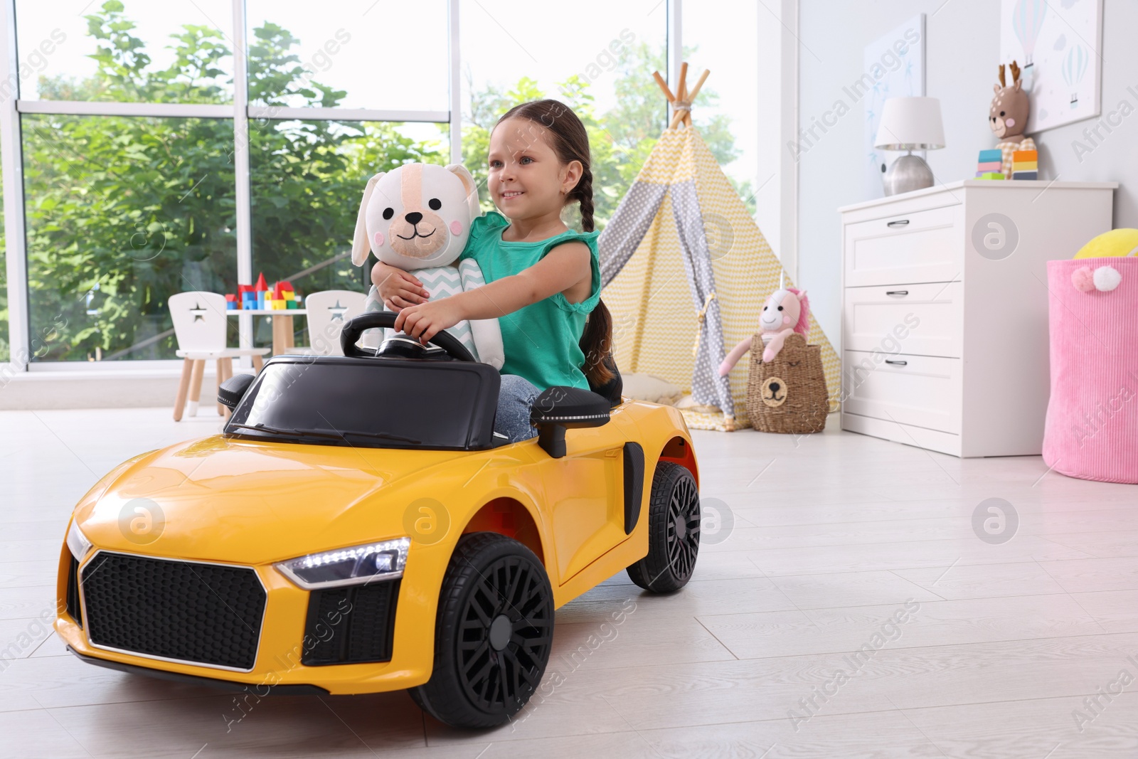 Photo of Adorable child with toy driving car in room at home