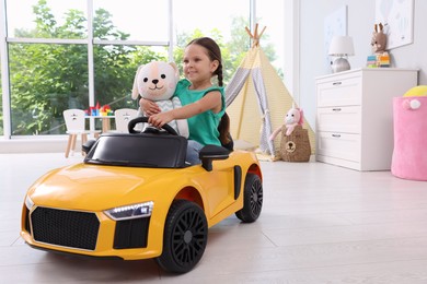 Adorable child with toy driving car in room at home