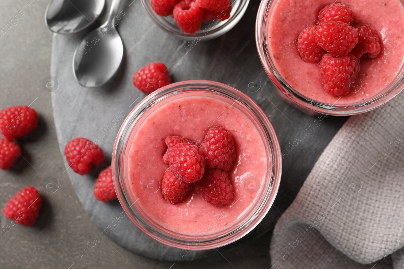 Photo of Delicious raspberry mousse served on grey table, flat lay