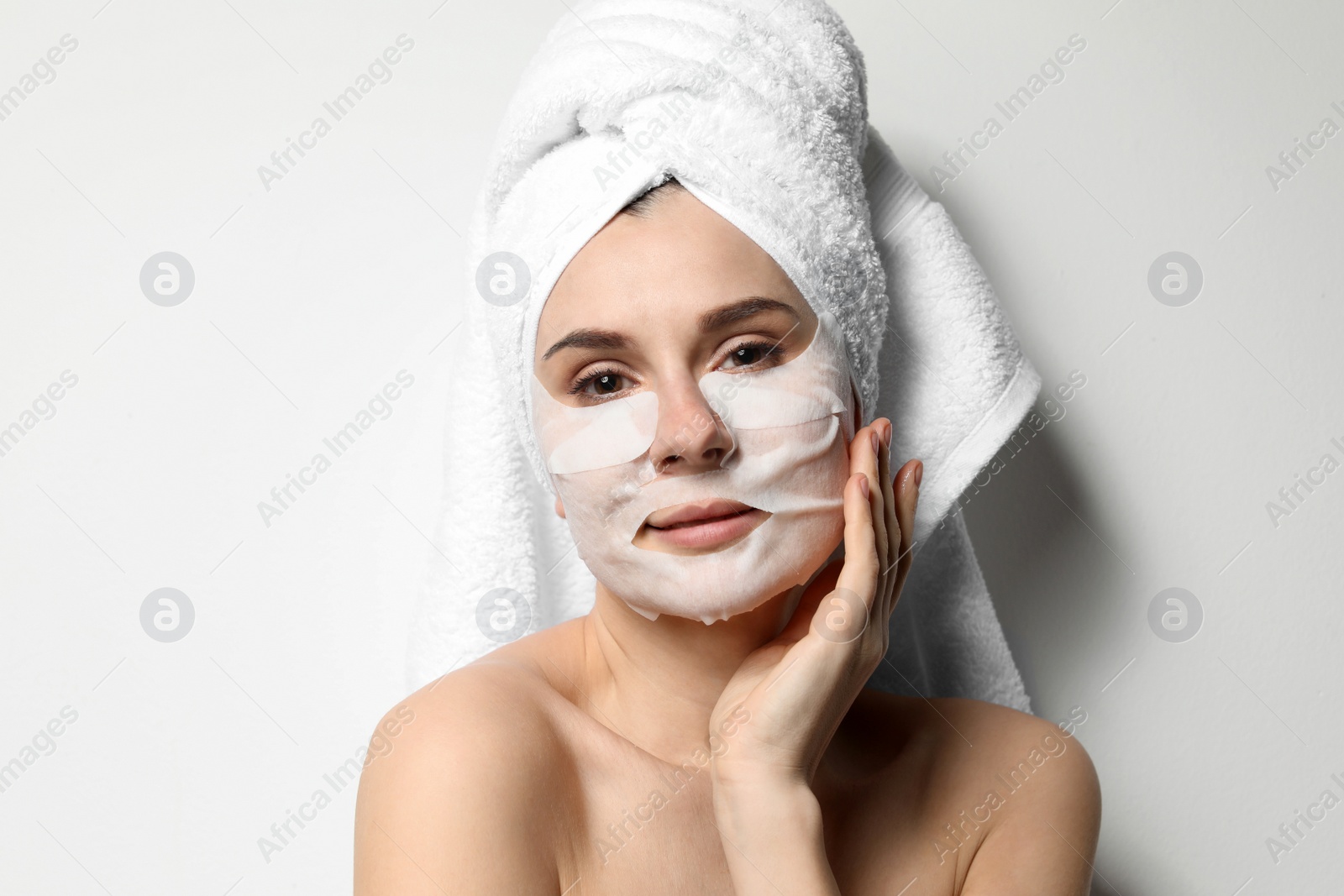 Photo of Beautiful woman with cotton face and eye masks against light background