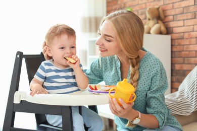 Photo of Woman feeding her child in highchair at home. Healthy baby food