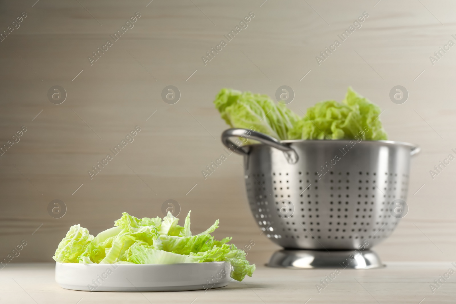 Photo of Cut fresh ripe Chinese cabbage on white table against light wooden background. Space for text