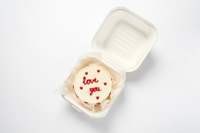 Photo of Bento cake with Love You text in takeaway box on white table, top view. St. Valentine's day surprise