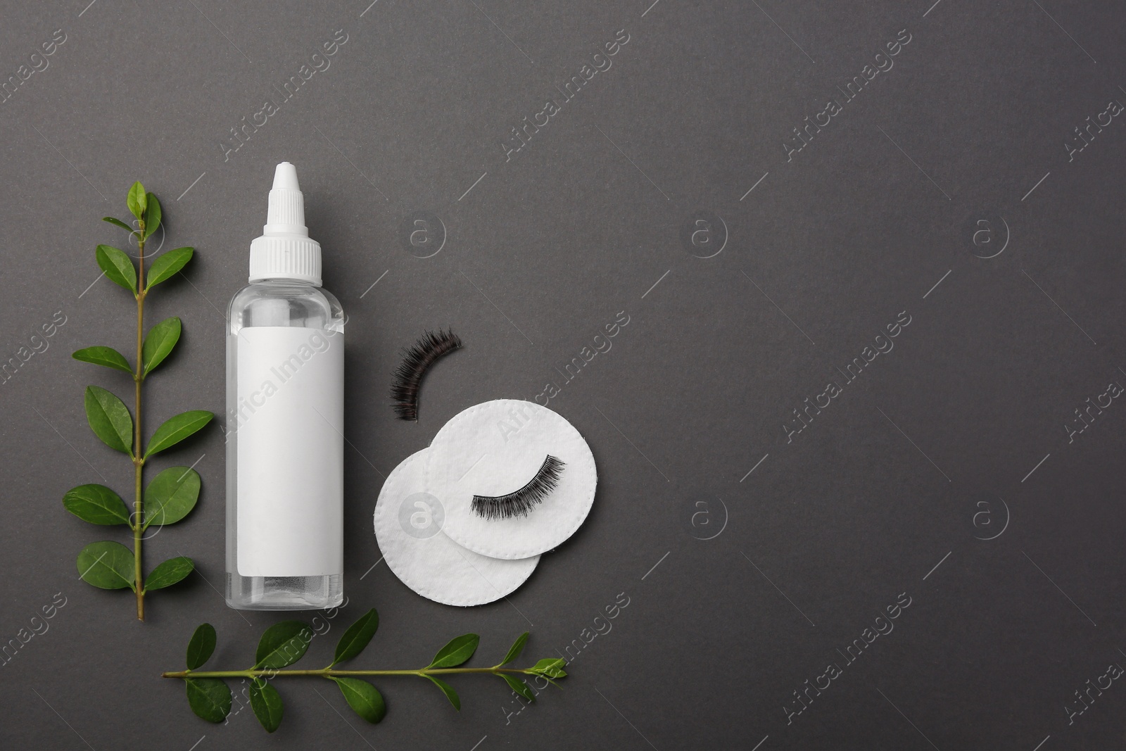 Photo of Flat lay composition with makeup remover and false eyelashes on dark grey background. Space for text