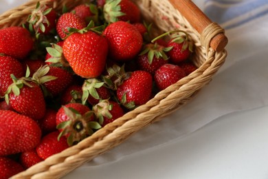 Photo of Wicker basket with ripe strawberries and napkin on white table, above view