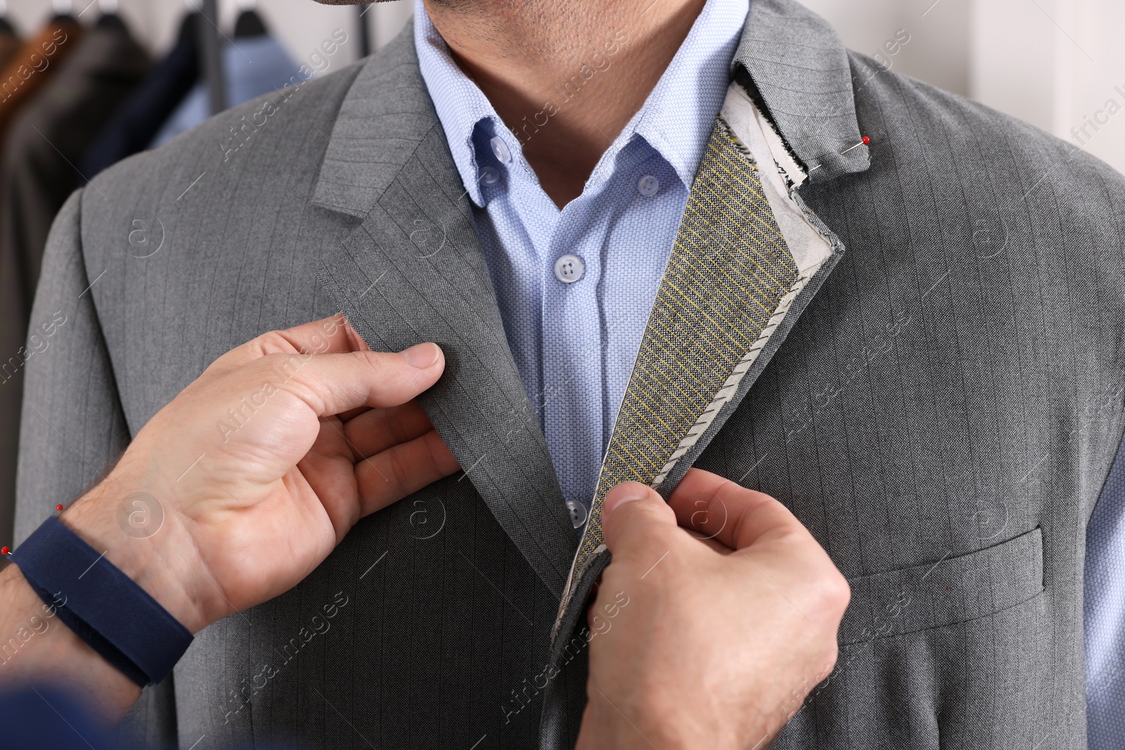 Photo of Professional tailor working with client in atelier, closeup